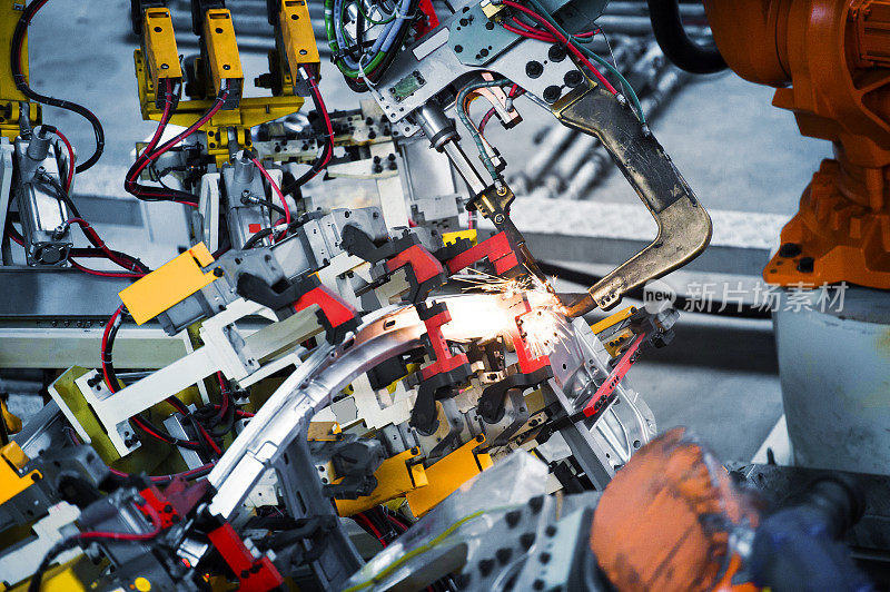 在汽车制造工厂，机器人手臂正在焊接车身焊点，使车身更坚固。