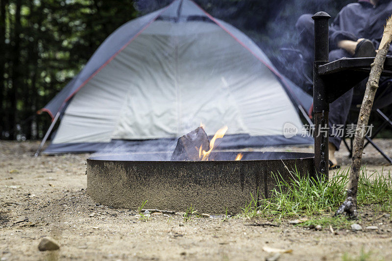在森林里露营时，一名男子坐在篝火旁