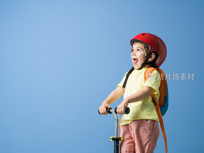 小男孩戴着头盔和他的滑板车摆姿势