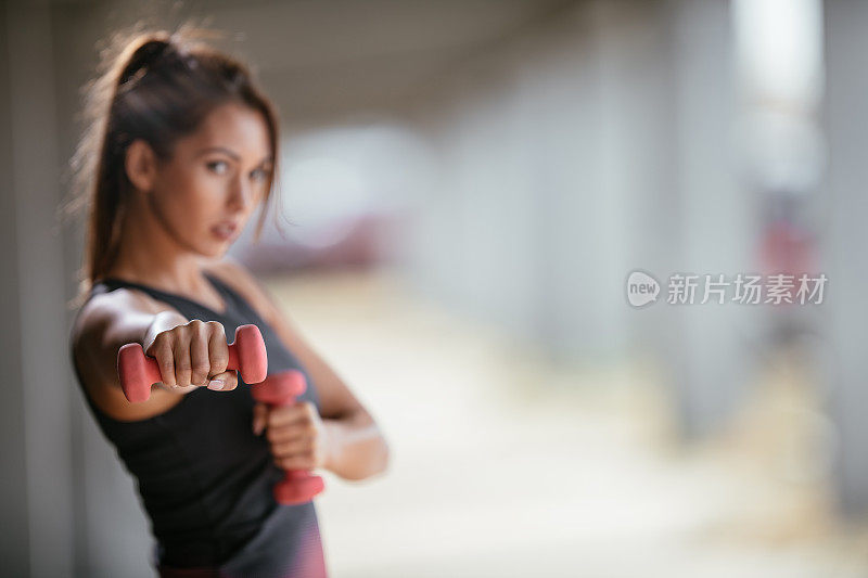 年轻的健身女性用哑铃锻炼