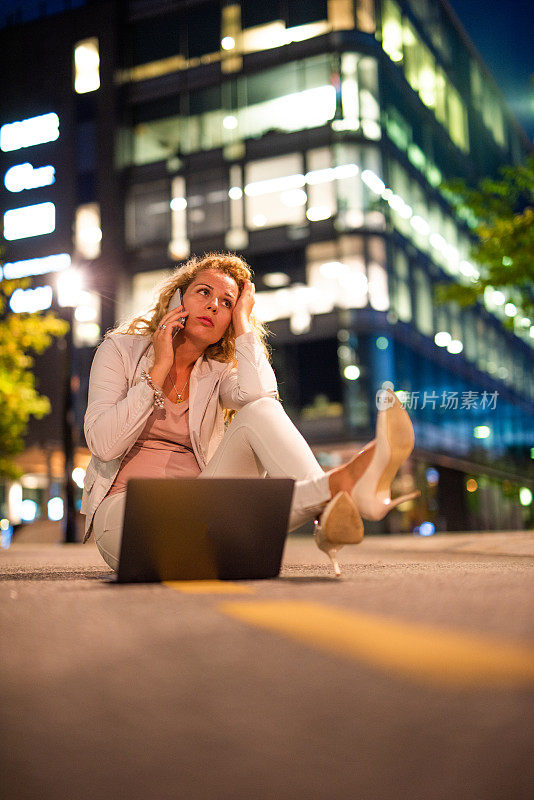 女商人坐在街上打手机。