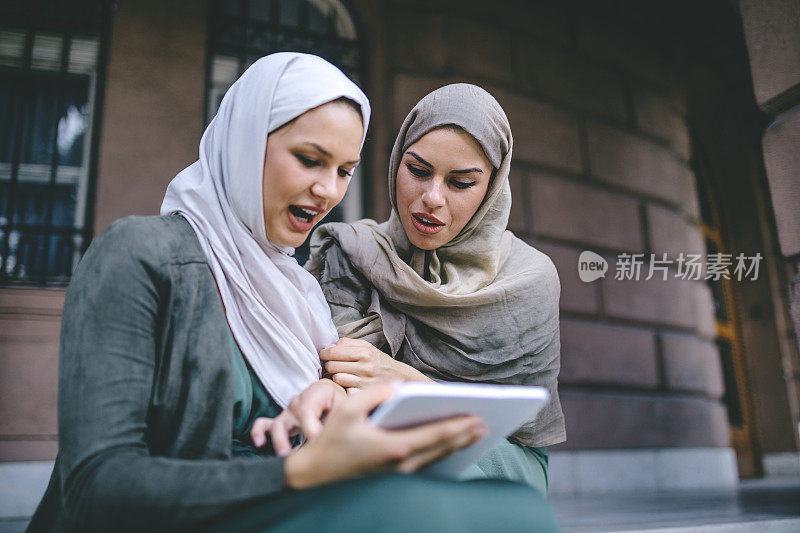 兴高采烈的阿拉伯妇女正在看数码平板电脑