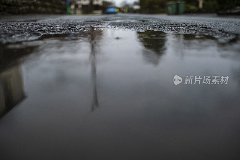 在一个阴雨绵绵的冬日，乡间小路中间的水坑。