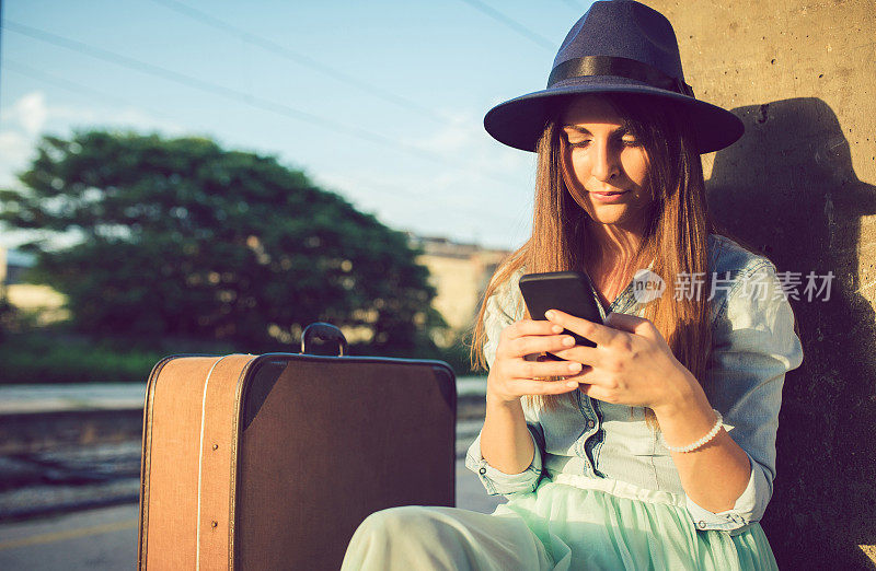 一名年轻女子在火车站等候时使用手机。