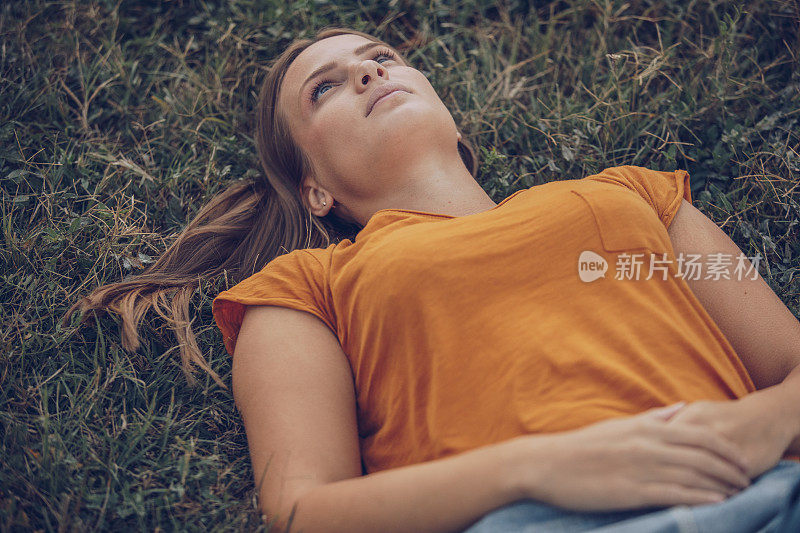 放松的年轻女子躺在草地上