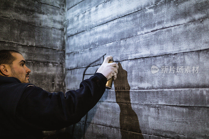 涂鸦艺术家在混凝土墙上为他的艺术作品制作轮廓线