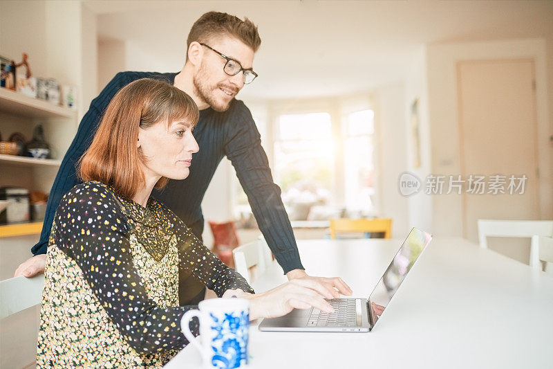 夫妇放松在家网上购物与笔记本电脑。