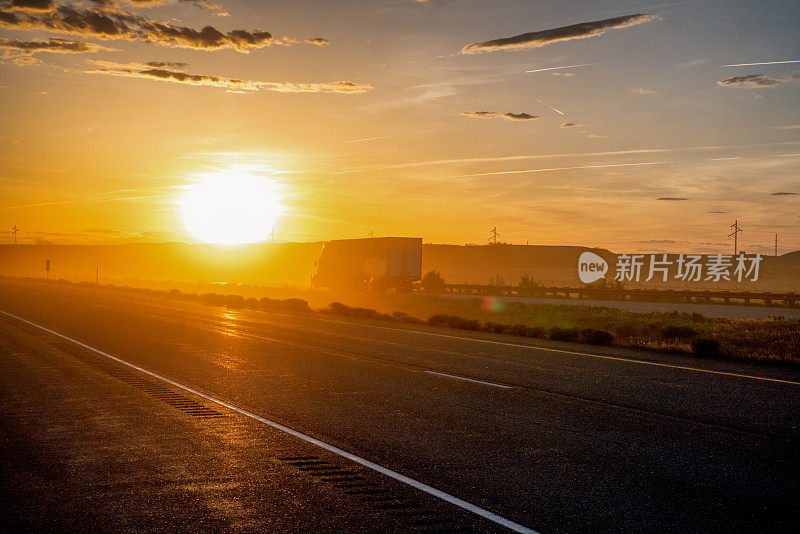 在一个戏剧性的天空下的黄昏高速公路上的长途半挂车