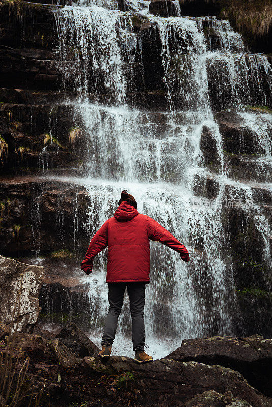 瀑布边穿着红色夹克的女孩