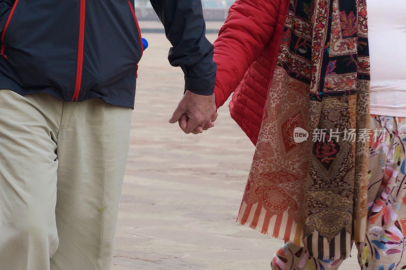 这是一对印度异性恋夫妇手牵着手游览印度阿格拉泰姬陵的照片