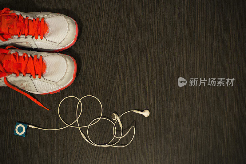 木地板背景上的跑鞋和mp3播放器