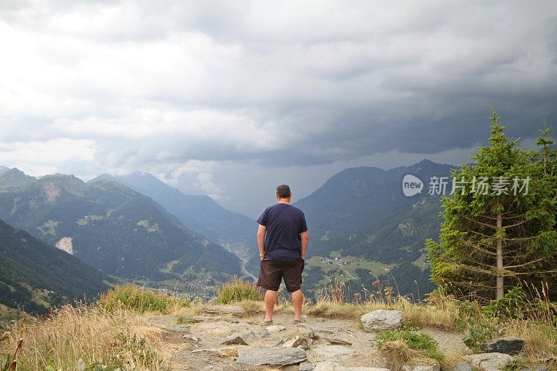 一个成熟的男人站在瑞士圣哥达山口。