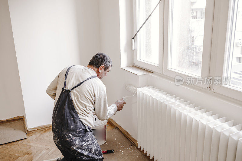 房屋油漆工用油漆滚筒粉刷家庭内部的白墙