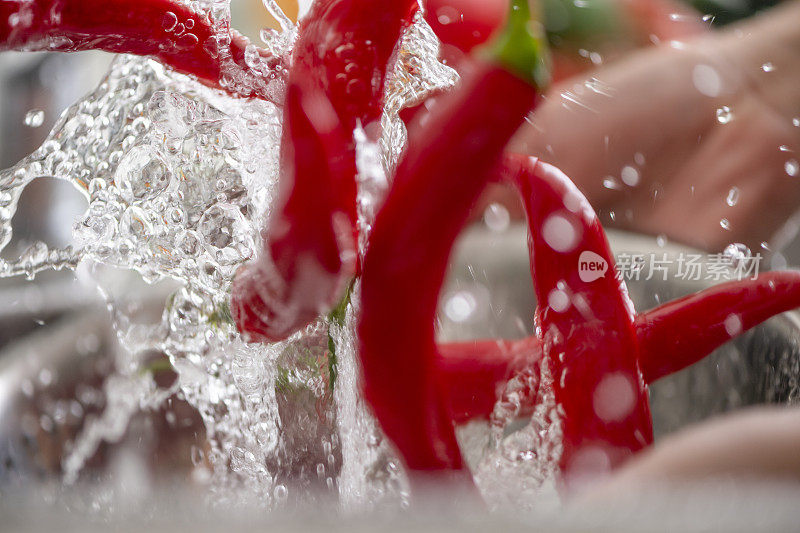女人用水槽里的滤锅清洗鲜红的辣椒。