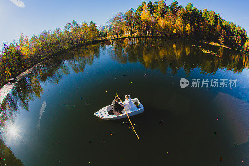 一对美丽的年轻夫妇在池塘上的小船上航行