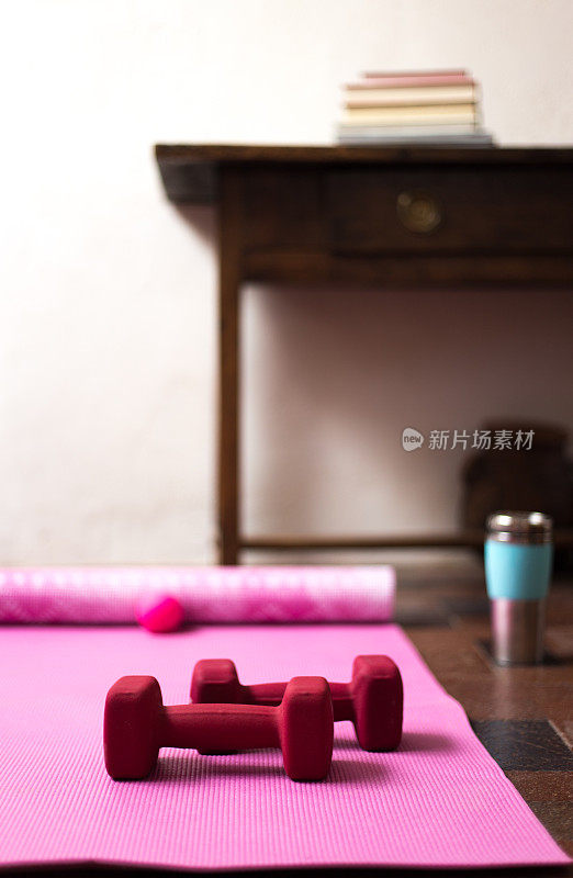 用粉色瑜伽垫和红色哑铃在家锻炼