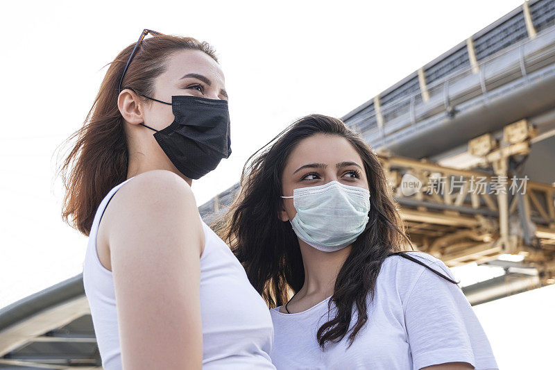 2019冠状病毒病大流行的新冠病毒，城市街道上的年轻女孩戴着口罩，以防止2019冠状病毒病的传播