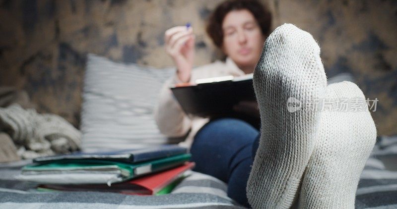 成熟的女人在家工作。注重脚上穿的羊毛手工袜子