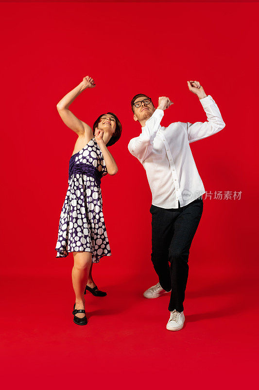 老式时尚的年轻夫妇在红色背景上跳舞