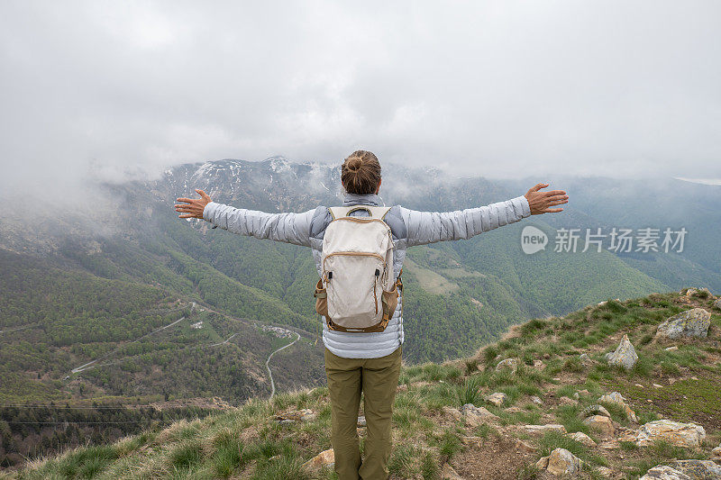 一个徒步旅行者双臂伸开站在山顶上