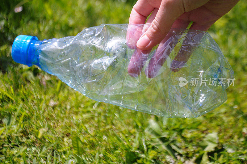 手拿着塑料水瓶在公园里