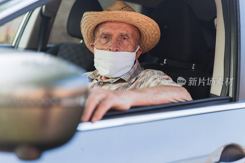 老人开车时戴着防护面具和草帽