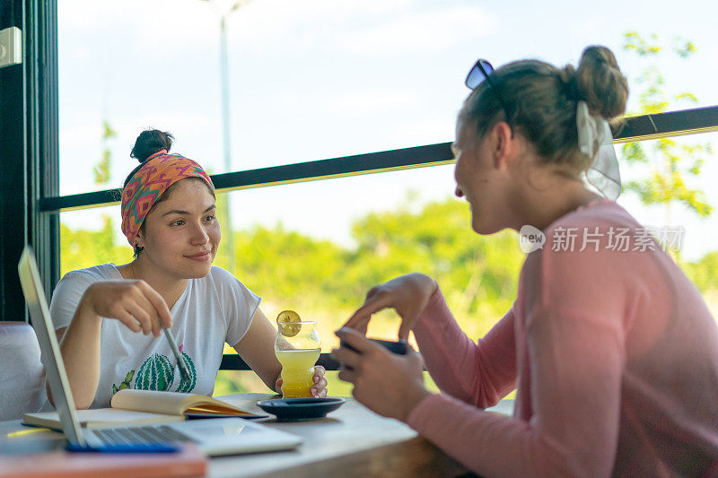 两个年轻女人和她的朋友在咖啡馆里开会