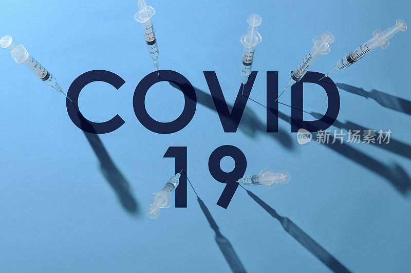 注射器上的针头刺入单词COVID-19的每个字母。