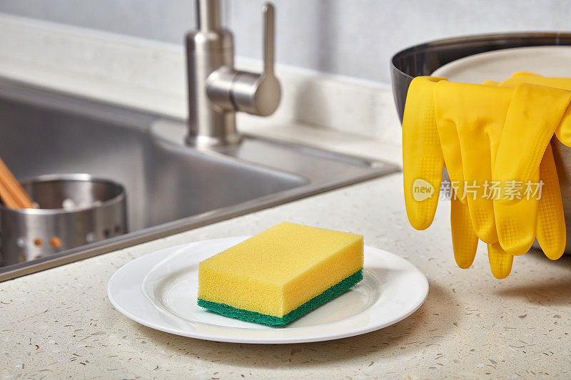 厨房水槽旁的黄色清洁海绵和橡胶手套