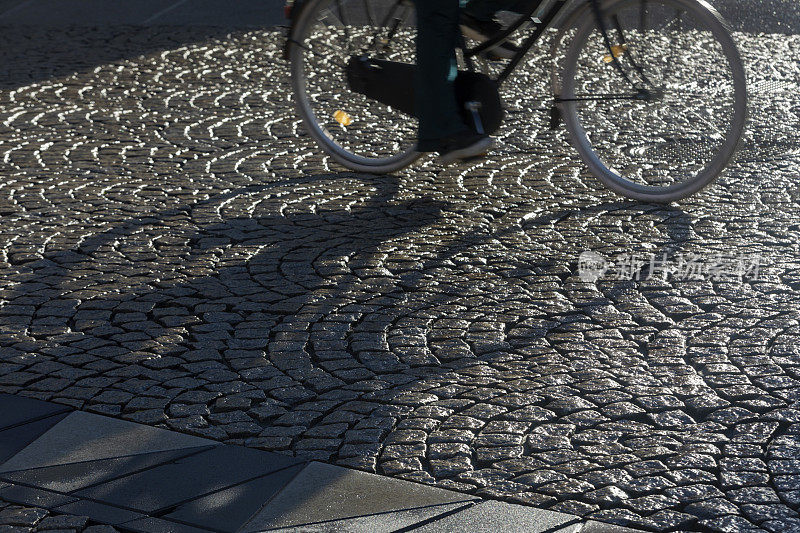 一个骑自行车的人在潮湿街道上的影子