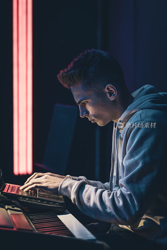 一个年轻人坐在黑屋子里，拿着一台笔记本电脑。