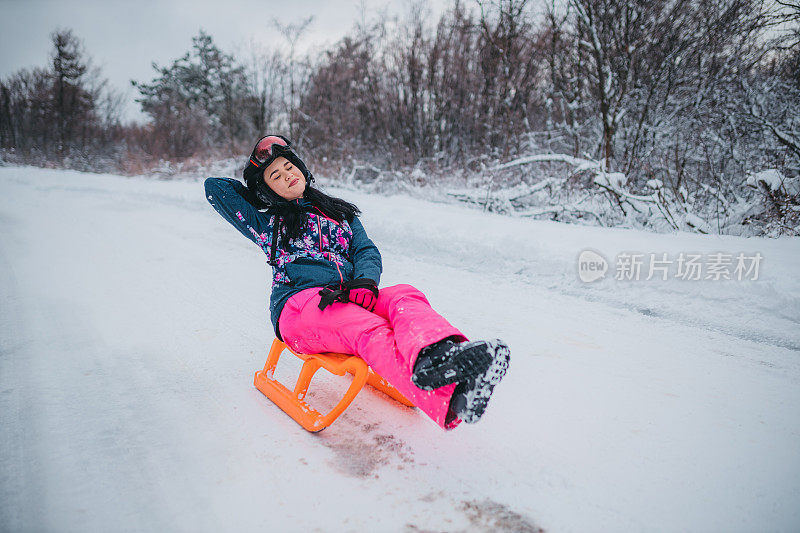 年轻女子滑雪橇下山