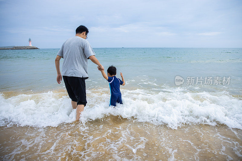 父亲和儿子在沙滩上玩水