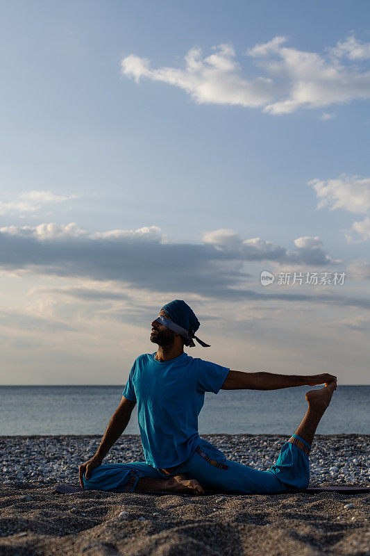 在日出或日落的时候，健康的年轻人在平静的海边练习瑜伽