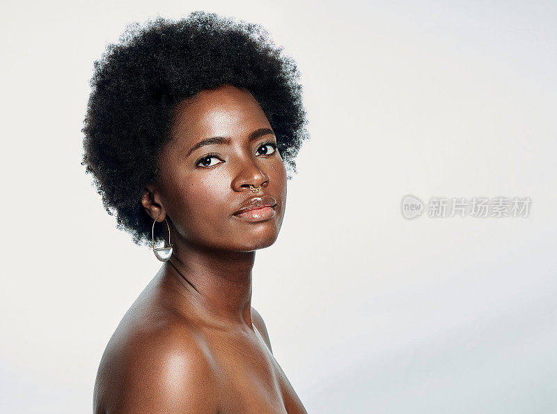 一个美丽的非洲女人的肖像与一个自然的爆炸头和发光的皮肤对一个孤立的白色背景与copyspace。黑人女性对她日常护肤的结果很满意