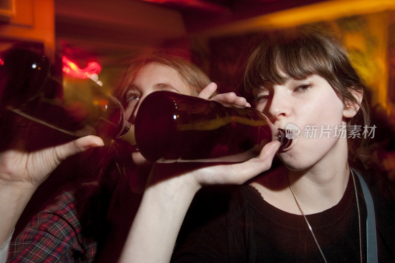 两个迷人的年轻女人在酒吧喝啤酒