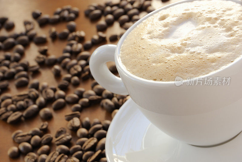 在白色的茶杯和茶碟里，用咖啡豆泡着起泡的咖啡