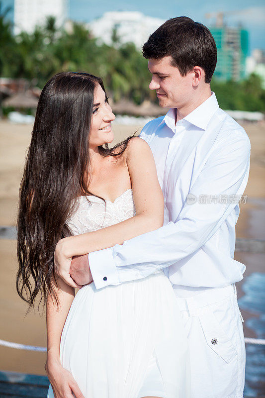 新婚夫妇在豪华度假村举行婚礼后。浪漫的新娘和新郎在海边放松。蜜月。