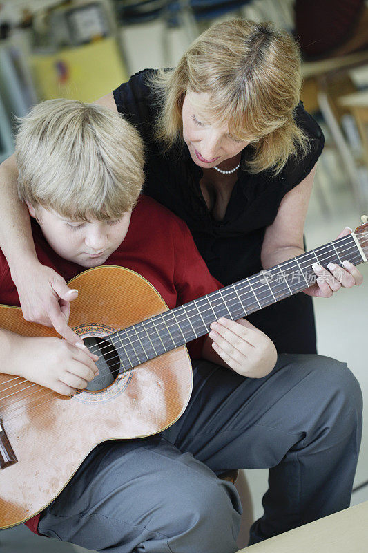 在音乐课上学习弹吉他的男孩