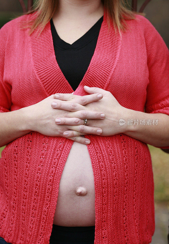 孕妇的肚子在敞开的毛衣