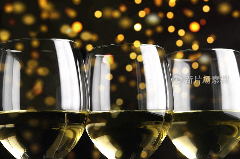 三杯白葡萄酒映衬着闪烁的黄色灯光