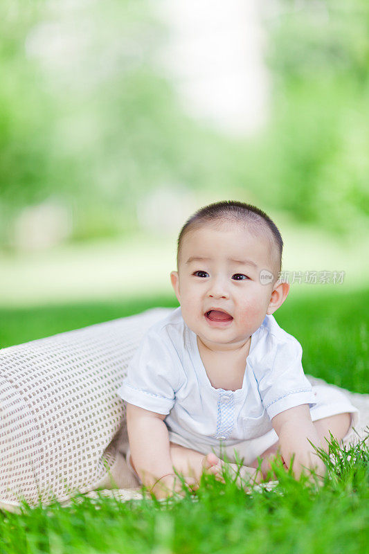 可爱的亚洲小男孩坐在草坪上
