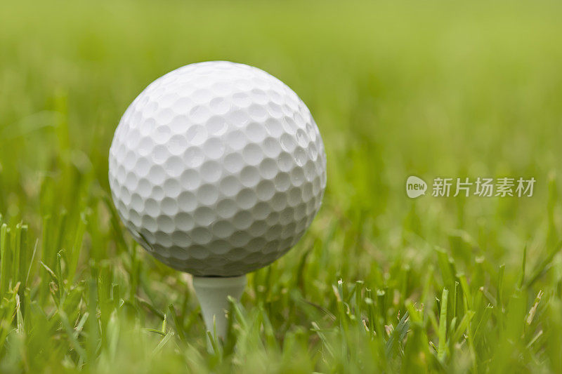 高尔夫球与绿色草地的球座的特写
