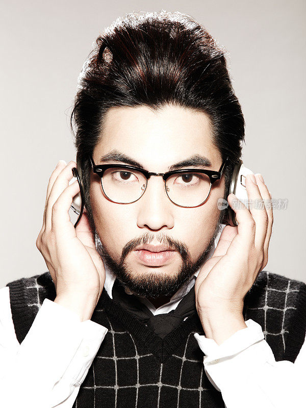 年轻的亚洲男人戴着耳机和时髦的眼镜