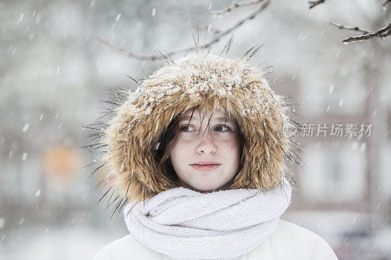 雪下穿着白色夹克的漂亮少女