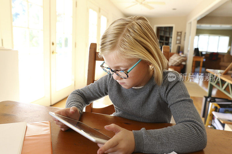 年轻女孩在她的数字平板电脑上工作