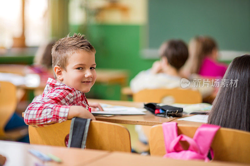 在学校里，快乐的小男孩转向镜头。