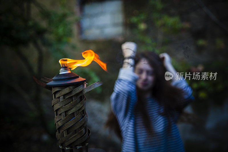 一个少女在花园里举着燃烧的火炬