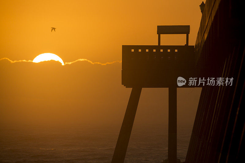 日出的山峰在云黄色橙色的天空与剪影码头