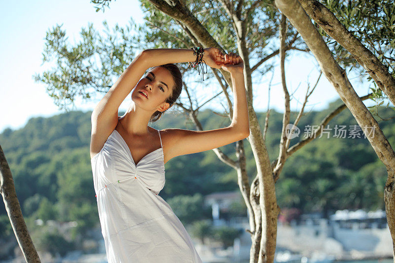 美丽的女孩，穿着白色的裙子，拿着橄榄树的树枝